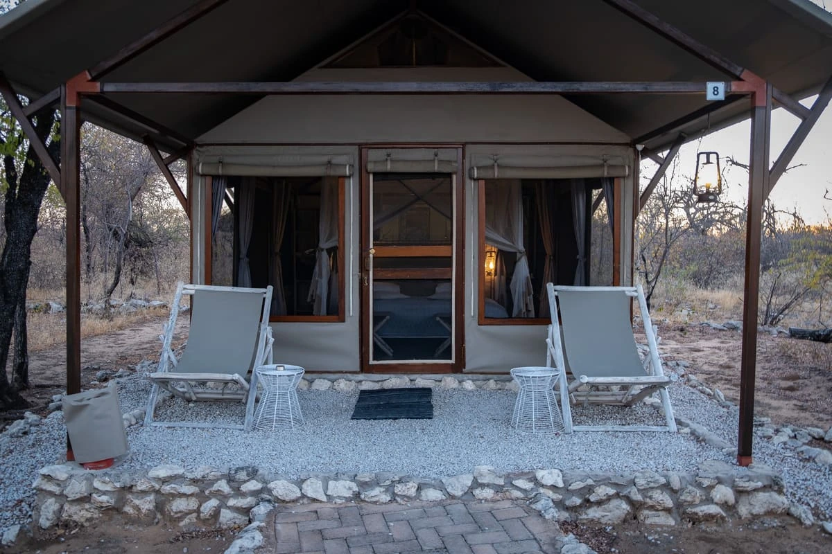 Extérieur d'une tente de luxe avec terrasse en gravier et deux chaises longues au Mushara Bush Camp, à l'entrée du parc d'Etosha