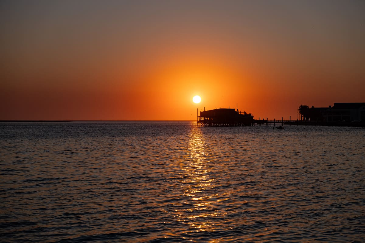 Dîner au coucher du soleil à Walvis Bay : vue sur le restaurant The Raft depuis la promenade de la lagune.