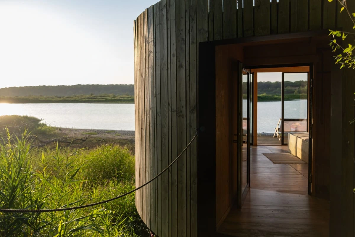 Cabane en bois de l'Aquascope de Virelles ouverte sur le lac au coucher du soleil